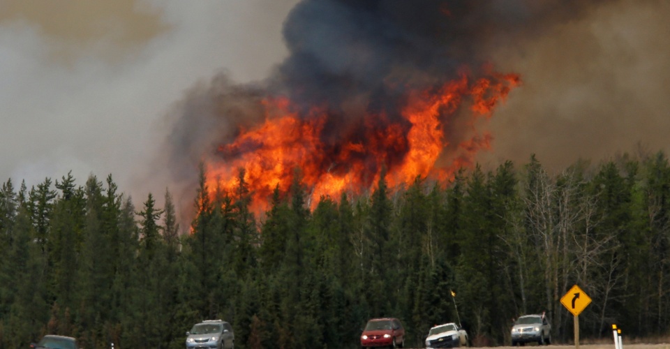 A wildfire burns as evacuees who were stranded north of Fort McMurray, Alberta, Canada head south of Fort McMurray on Highway 63, May 6, 2016. REUTERS/Chris Wattie/File Photo