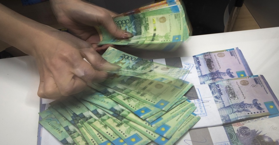 A cashier checks Kazakhstan's Tenge currency notes in a Eurasian Bank branch in Almaty January 15, 2015. Growing damage from Russia's financial crisis on neighbouring former Soviet states could bury President Vladimir Putin's dream of creating an economic union to rival the United States and European Union. From Belarus on the European Union's fringe to Kazakhstan on the border with China, some of those once firmly in Moscow's grip are now questioning whether Russia has what it takes to lead.  REUTERS/Shamil Zhumatov (KAZAKHSTAN - Tags: BUSINESS POLITICS) - RTR4LIM1